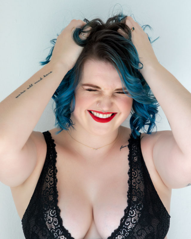 blue haired women laughing wearing black bra